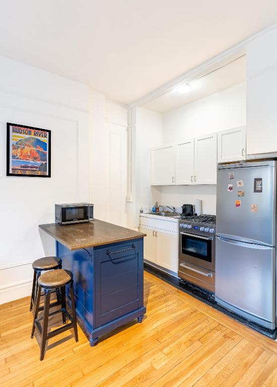 kitchen featuring appliances with stainless steel finishes, a kitchen breakfast bar, white cabinetry, and light wood-type flooring