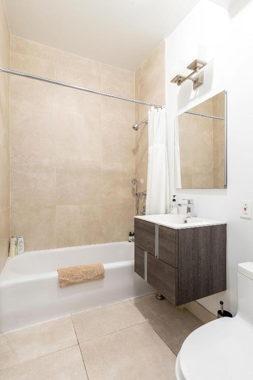 full bathroom with shower / bath combination with curtain, vanity, toilet, and tile patterned floors