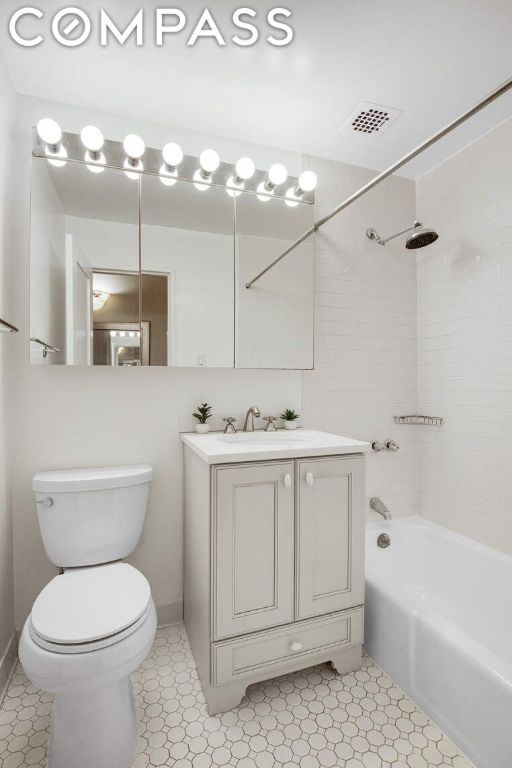 full bathroom with toilet, tiled shower / bath, and vanity