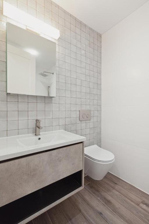 bathroom featuring tile walls, toilet, and vanity