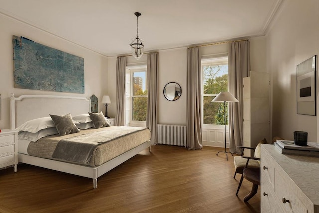 bedroom with dark wood-type flooring, ornamental molding, and radiator heating unit