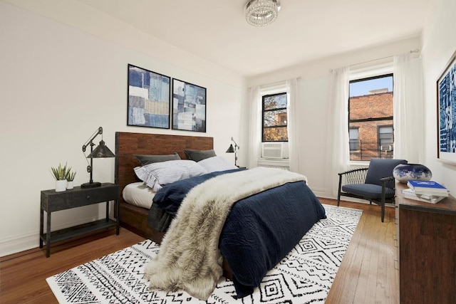 bedroom featuring cooling unit, baseboards, and wood finished floors