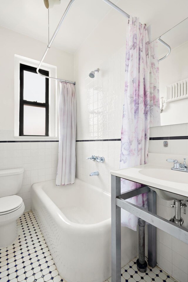 full bathroom featuring toilet, shower / bathtub combination with curtain, a wainscoted wall, and tile walls