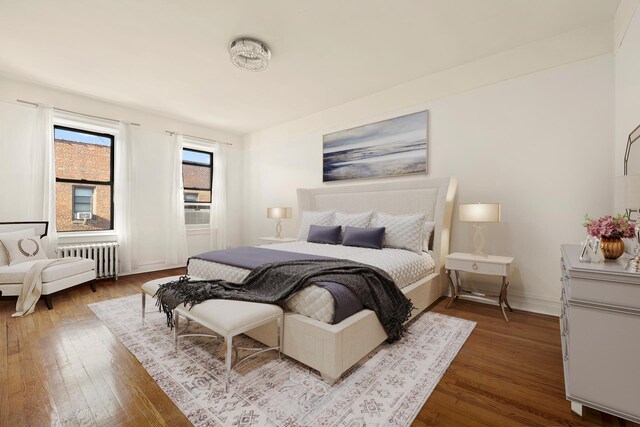 bedroom featuring baseboards, radiator heating unit, and hardwood / wood-style flooring