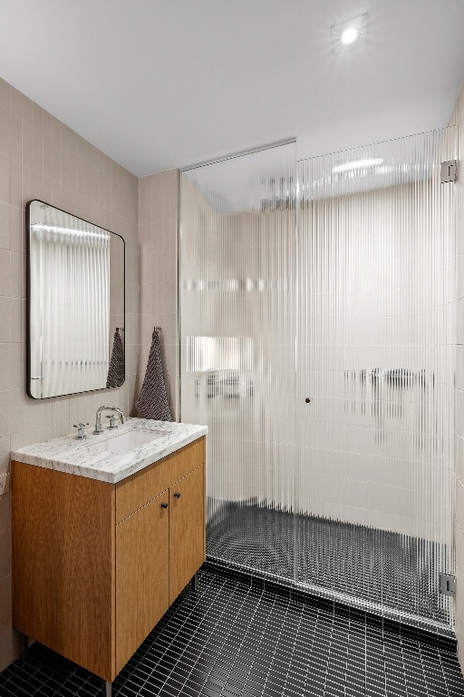 bathroom with walk in shower, vanity, tile patterned flooring, and tile walls