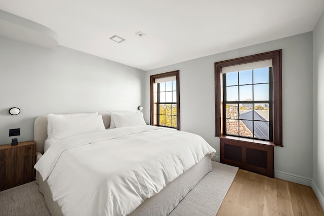 bedroom with radiator heating unit and light hardwood / wood-style floors