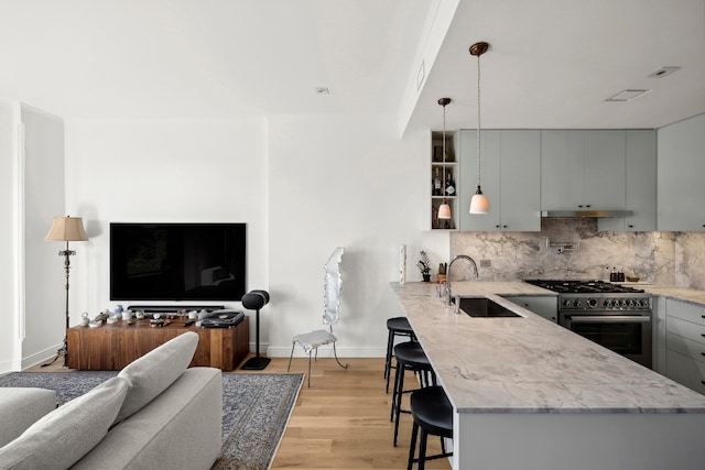 kitchen featuring sink, decorative light fixtures, a kitchen breakfast bar, gray cabinets, and kitchen peninsula