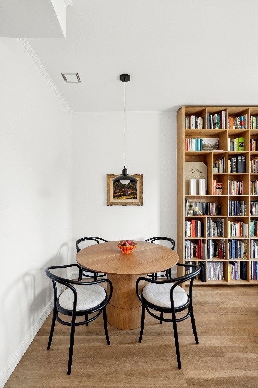 dining space with crown molding and light hardwood / wood-style floors