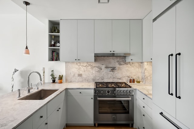 kitchen featuring sink, light stone counters, high end range, pendant lighting, and backsplash