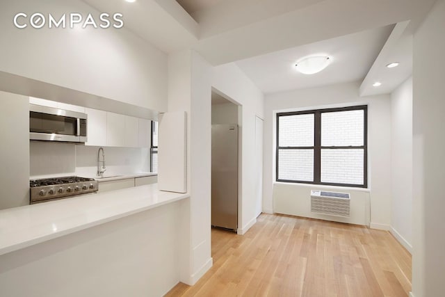 corridor featuring recessed lighting, light wood-style floors, an AC wall unit, a sink, and baseboards