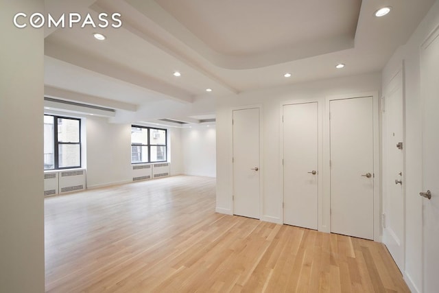 unfurnished room with light wood-style flooring, recessed lighting, baseboards, radiator, and beamed ceiling