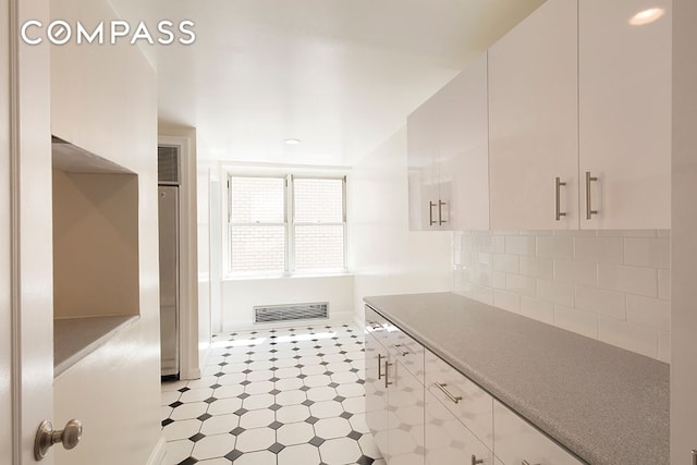 kitchen featuring visible vents, decorative backsplash, light countertops, light floors, and white cabinetry