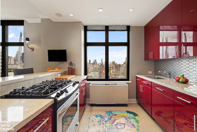 kitchen featuring tasteful backsplash, sink, a wall of windows, gas range, and a healthy amount of sunlight