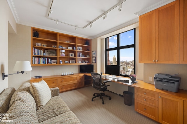 carpeted office space with ornamental molding, rail lighting, and built in desk