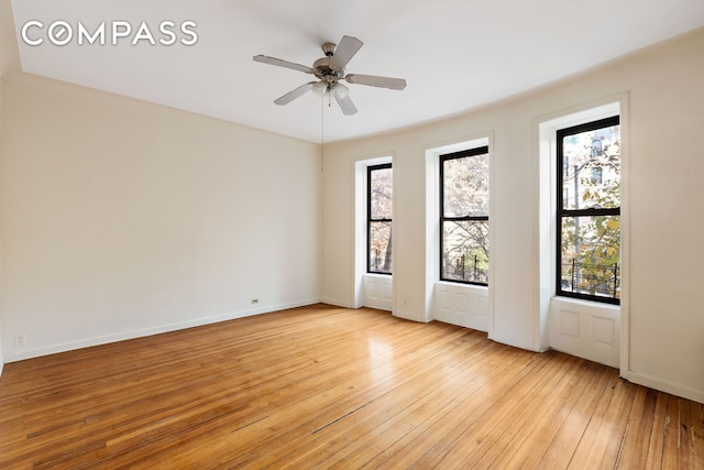 empty room with light wood finished floors, baseboards, and ceiling fan