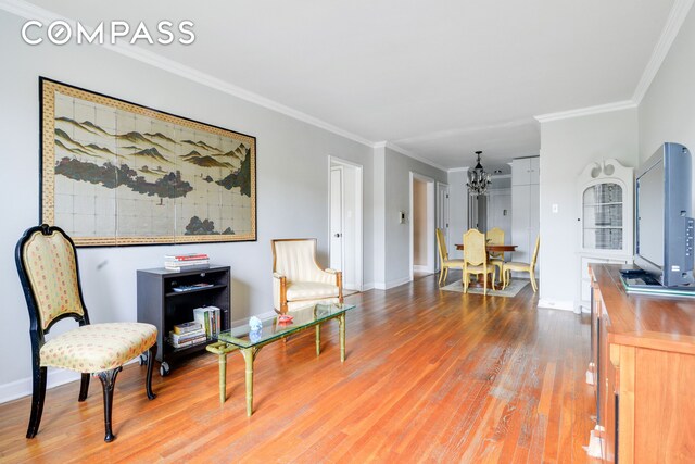 living area with crown molding and hardwood / wood-style flooring