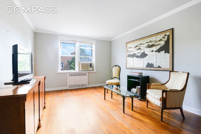 sitting room featuring radiator, baseboards, crown molding, and light wood finished floors