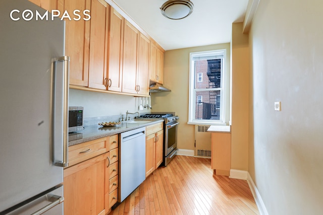 kitchen featuring under cabinet range hood, baseboards, light countertops, appliances with stainless steel finishes, and light wood-type flooring