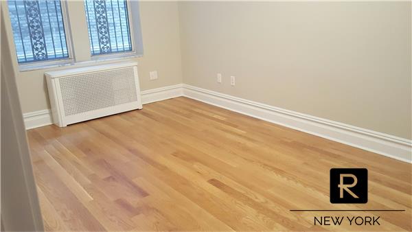 spare room featuring radiator heating unit, baseboards, and wood finished floors