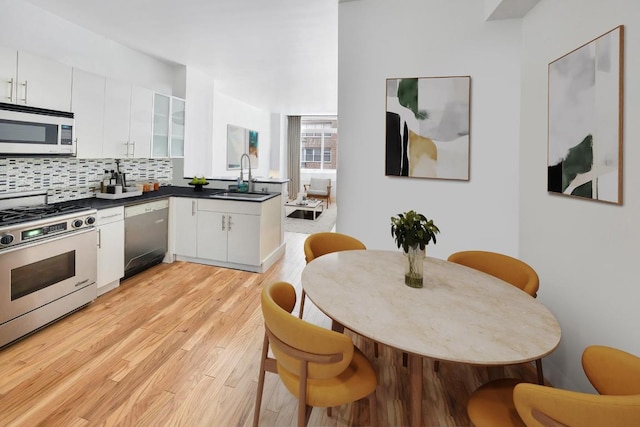 kitchen featuring decorative backsplash, sink, light wood-type flooring, appliances with stainless steel finishes, and white cabinets