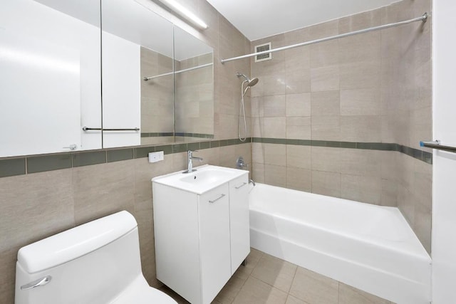 full bathroom featuring toilet, tile patterned flooring, tile walls, and tiled shower / bath