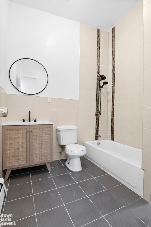 bathroom with tile walls, vanity, tile patterned flooring, and toilet