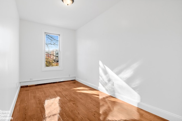 spare room with hardwood / wood-style floors and a baseboard heating unit