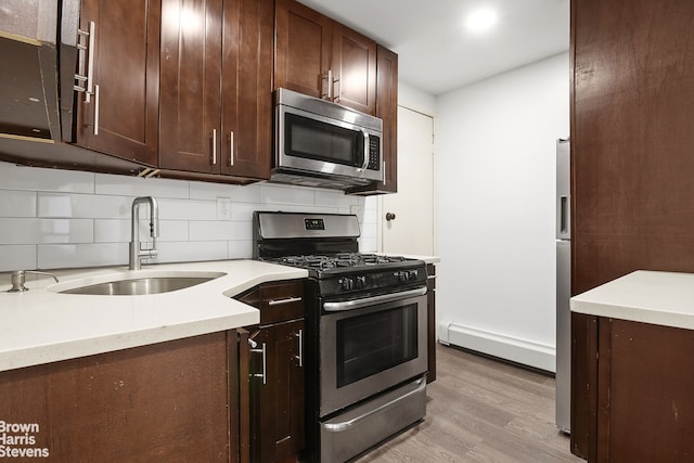 kitchen with tasteful backsplash, sink, stainless steel appliances, dark brown cabinets, and light wood-type flooring