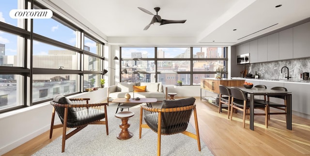 sunroom featuring a wealth of natural light, a city view, a ceiling fan, and a sink