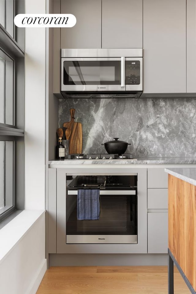 kitchen with stainless steel appliances, modern cabinets, decorative backsplash, and light countertops