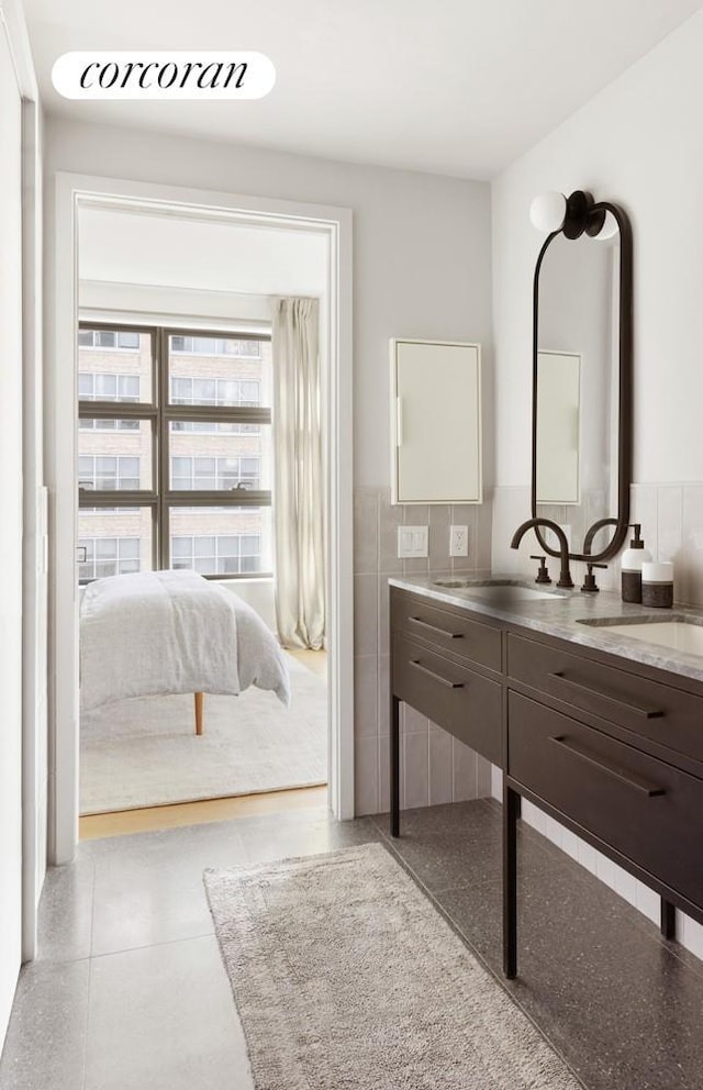 bathroom with a wainscoted wall, tile walls, and vanity