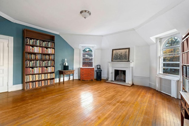 unfurnished room featuring wood-type flooring, radiator, ornamental molding, and built in shelves