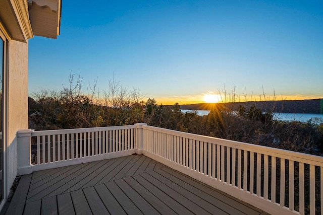 deck at dusk featuring a water view