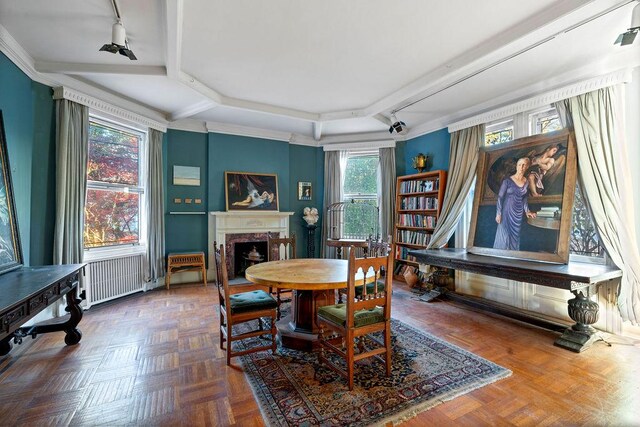 dining area with rail lighting, radiator heating unit, a premium fireplace, and parquet flooring