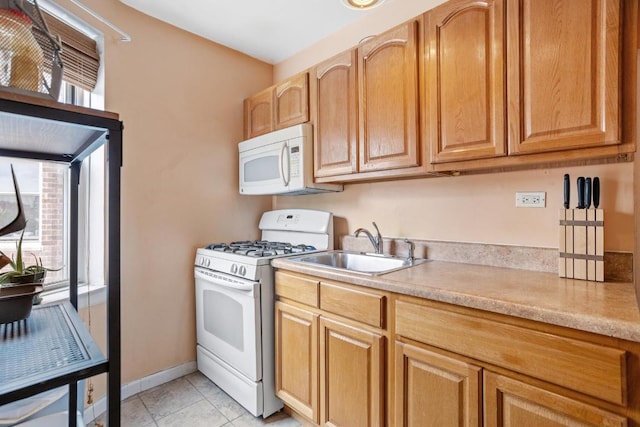 kitchen with white appliances, light tile patterned floors, baseboards, light countertops, and a sink