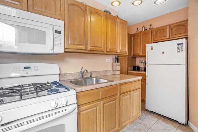 kitchen with light countertops, white appliances, light tile patterned flooring, and a sink