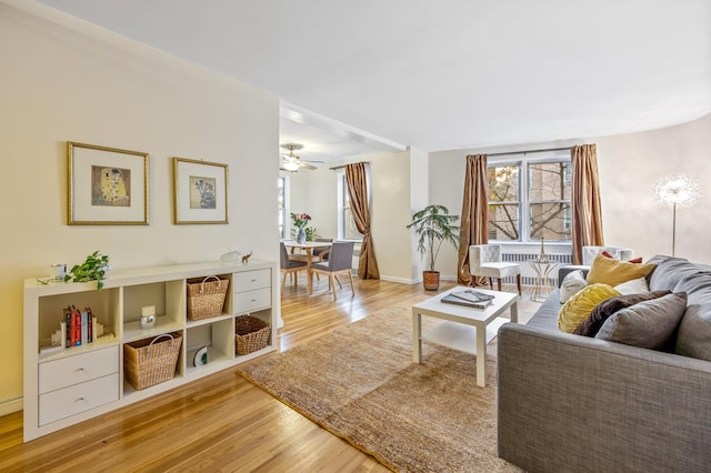 living area with ceiling fan, light wood finished floors, and baseboards