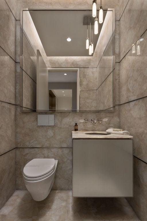 bathroom featuring toilet, vanity, and tile walls