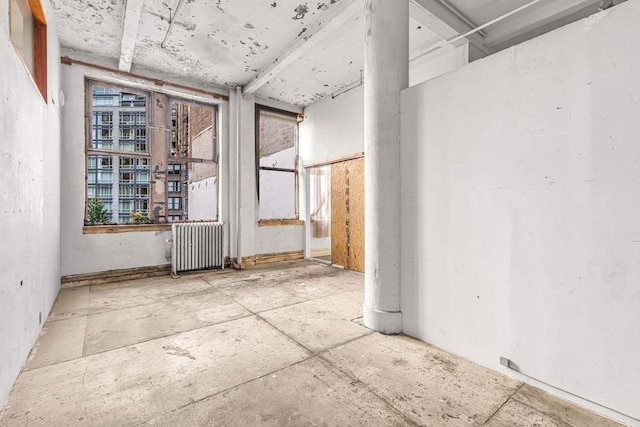 unfurnished sunroom with ceiling fan and beam ceiling