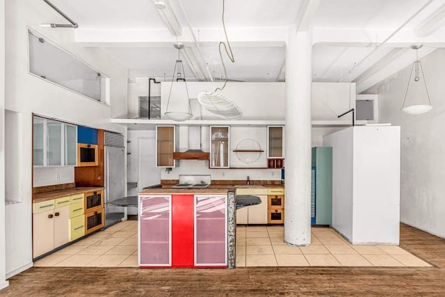 kitchen with premium range hood, a towering ceiling, sink, stainless steel built in fridge, and light tile patterned floors