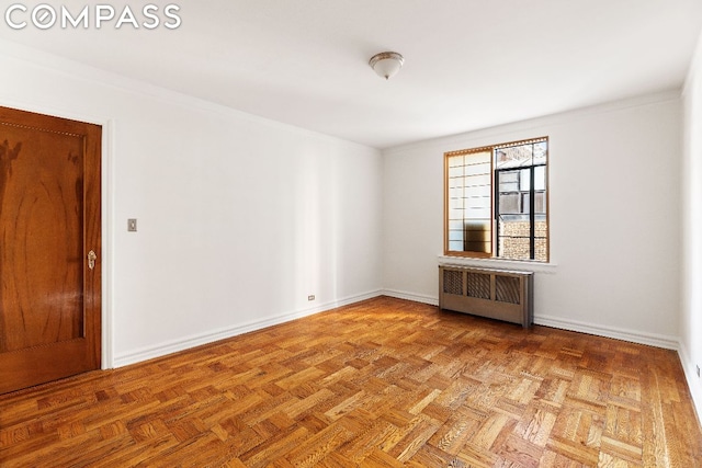 spare room featuring light parquet flooring, radiator heating unit, and ornamental molding