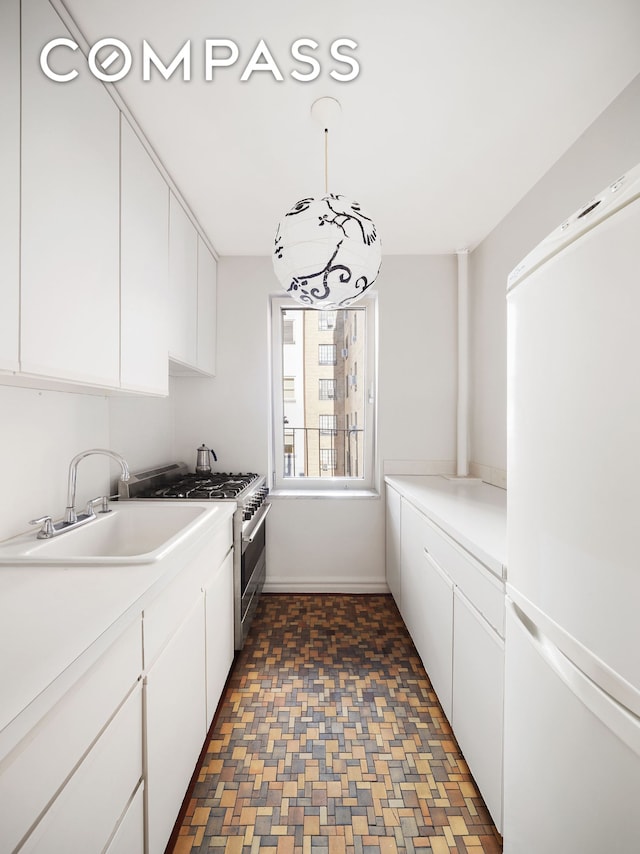 135 E 39th St Unit 5E, New York City, NY 10016 - kitchen with freestanding refrigerator, double oven range, white cabinets, light countertops, and pendant lighting