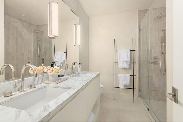 bathroom with double vanity, a shower stall, and a sink