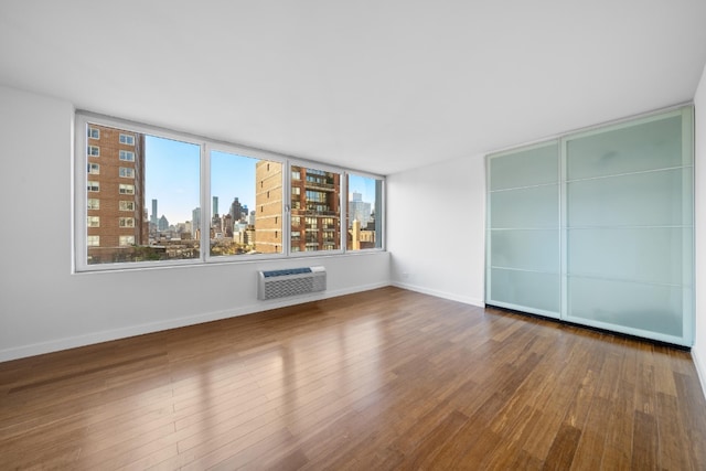 spare room with wood-type flooring and a wall unit AC