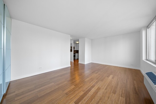 unfurnished bedroom with hardwood / wood-style flooring and a wall mounted AC