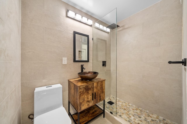 bathroom with vanity, toilet, tile walls, and a tile shower