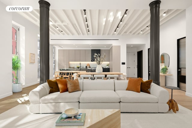 living room featuring visible vents, track lighting, baseboards, light wood-style floors, and ornate columns