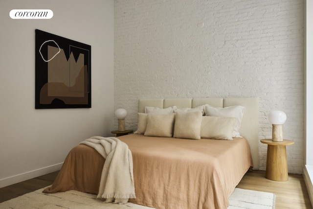 bedroom with baseboards, wood finished floors, and brick wall