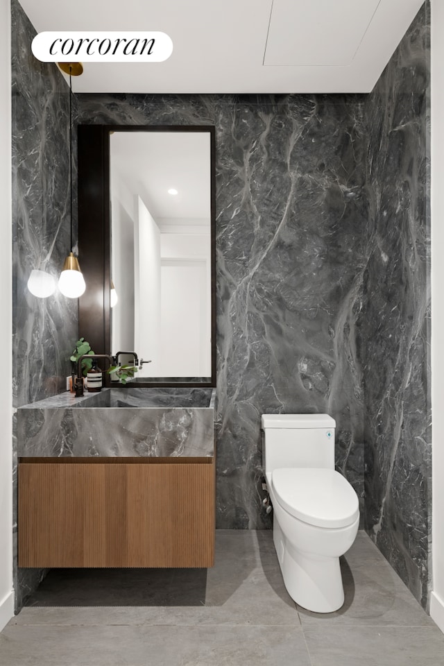 bathroom with vanity, toilet, tile walls, and stone wall