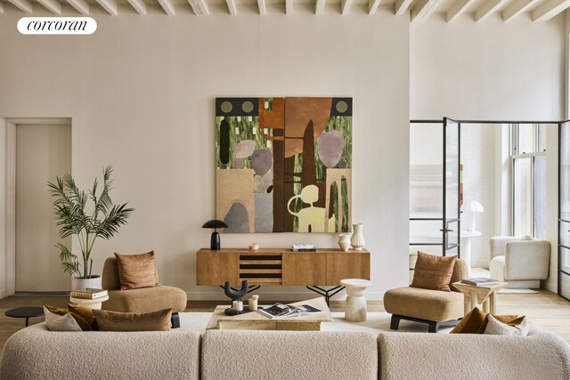 living area with beamed ceiling, visible vents, and wood finished floors